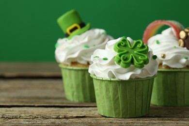 Photo of St. Patrick's day party. Tasty festively decorated cupcakes on wooden table, closeup. Space for text