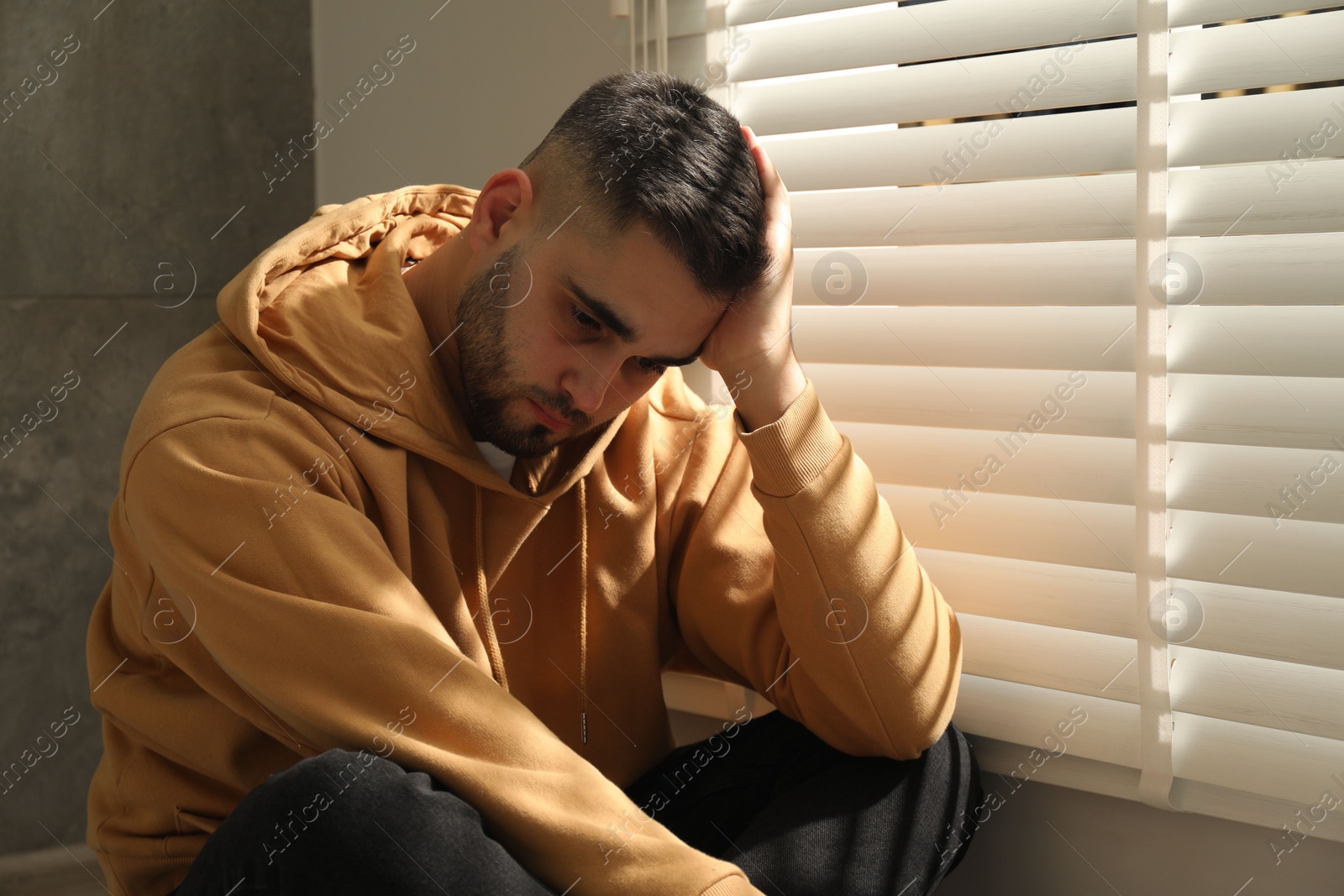 Photo of Sad young man and sitting near window