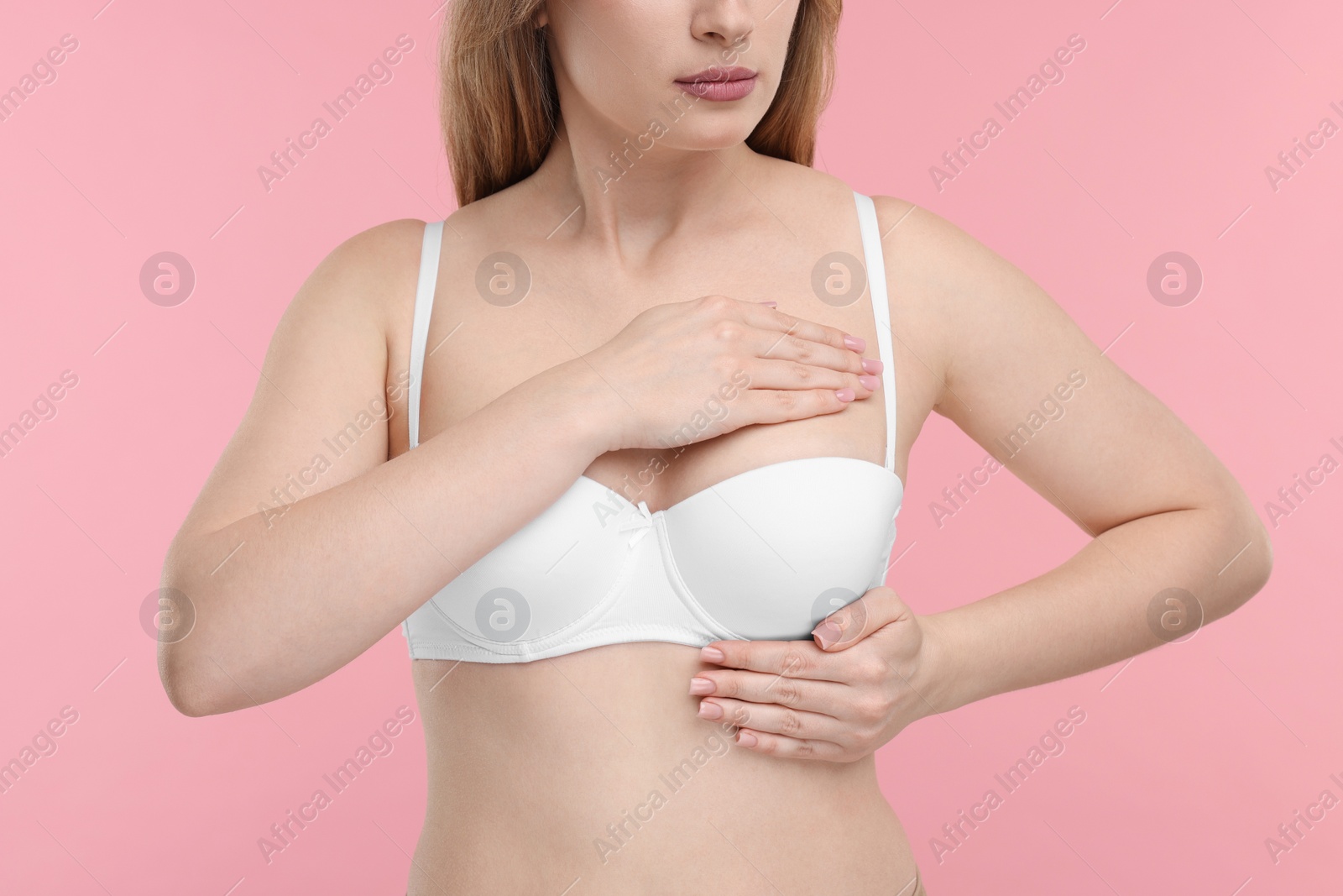 Photo of Mammology. Young woman doing breast self-examination on pink background, closeup