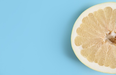 Photo of Fresh cut pomelo fruit on light blue background, top view. Space for text