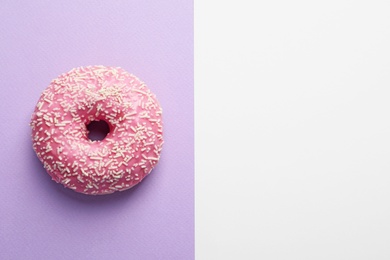 Photo of Delicious glazed doughnut with sprinkles on color background, top view