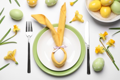 Photo of Festive Easter table setting with painted eggs and floral decor on white background, flat lay