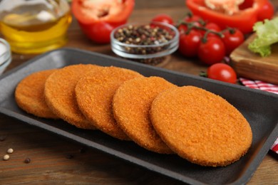 Photo of Uncooked breaded cutlets on wooden table. Freshly frozen semi-finished product