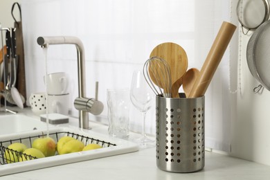 Photo of Holder with cooking utensils near sink on kitchen counter