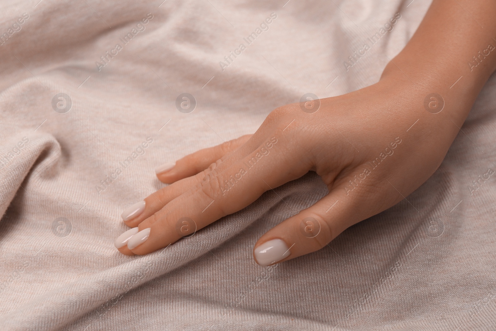 Photo of Woman touching soft beige fabric, closeup view