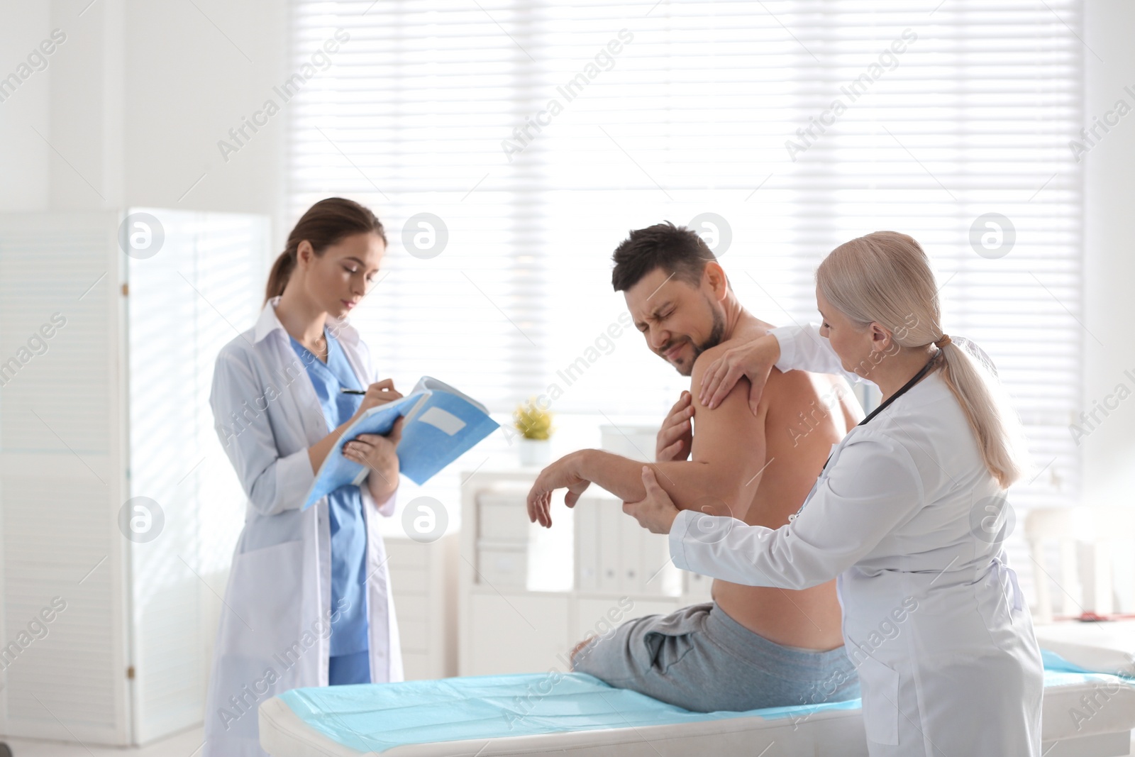 Photo of Female orthopedist examining patient's arm in clinic