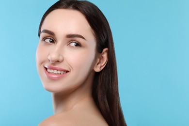 Portrait of beautiful young woman on light blue background. Space for text