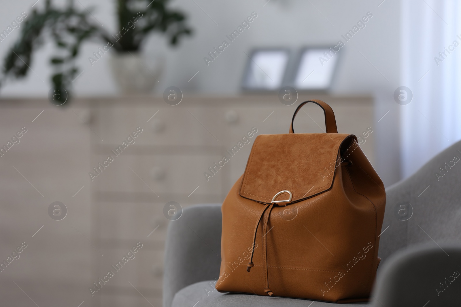 Photo of Stylish brown backpack on grey armchair indoors, space for text