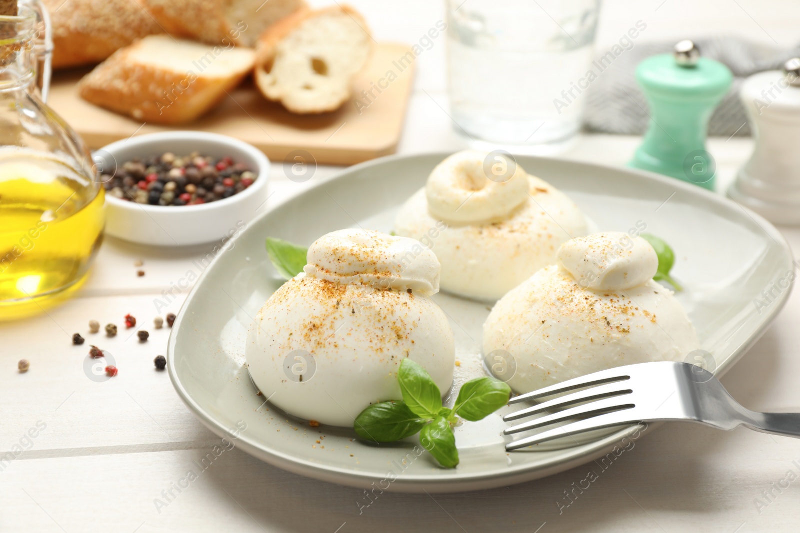 Photo of Delicious burrata cheese with basil on white wooden table, closeup