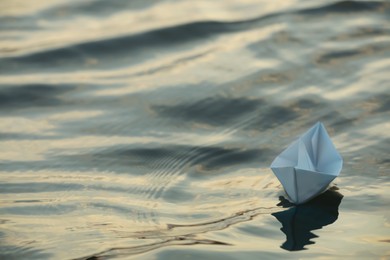 Paper boat floating on water outdoors. Space for text