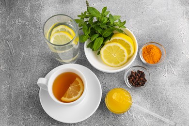 Photo of Cup with delicious immunity boosting tea and ingredients on grey table, above view
