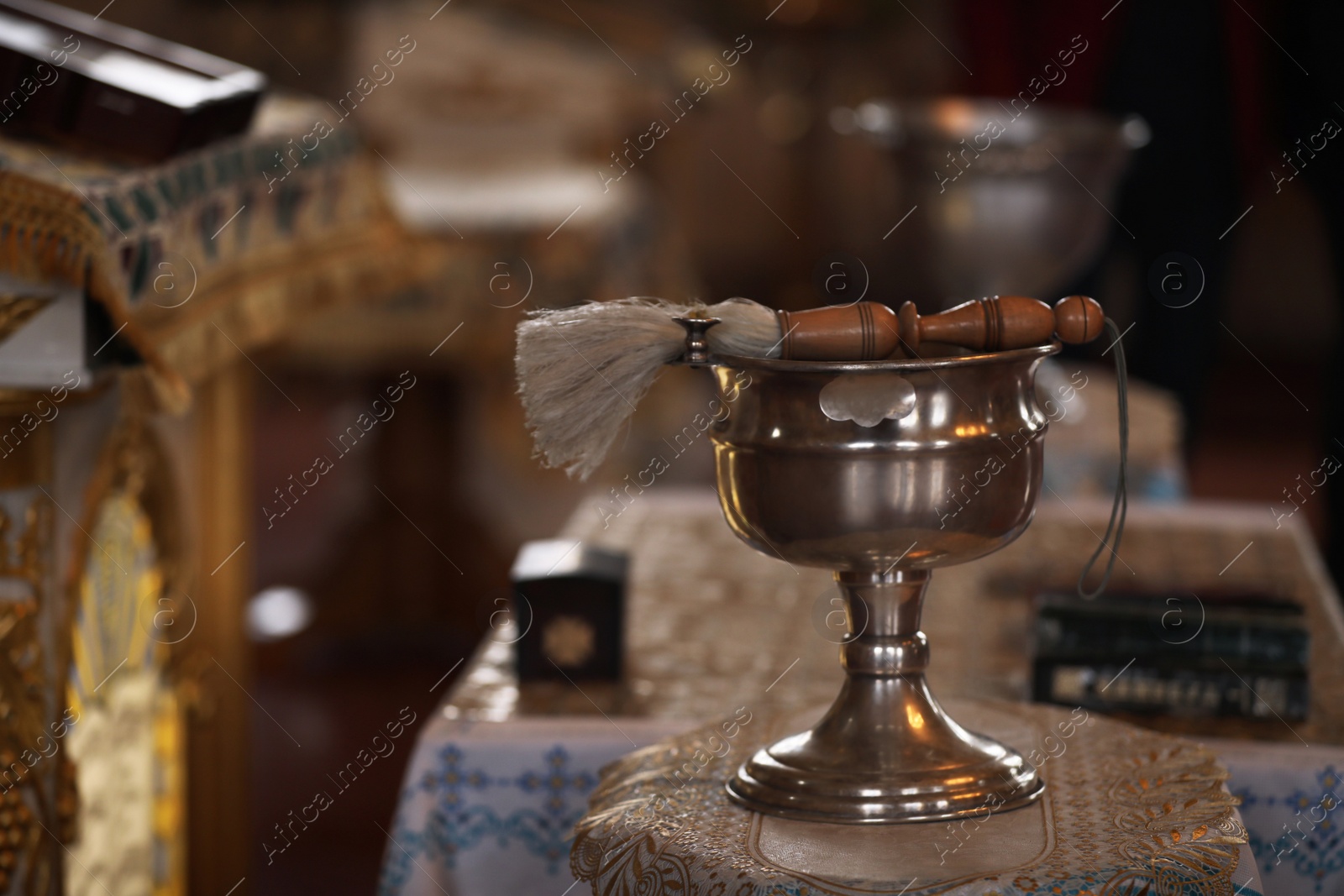Photo of Silver vessel with holy water and brush on stand in church, space for text. Baptism ceremony