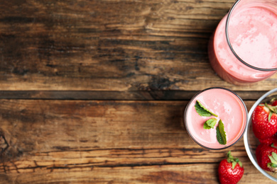 Photo of Tasty strawberry smoothies in glasses on wooden table, flat lay. Space for text