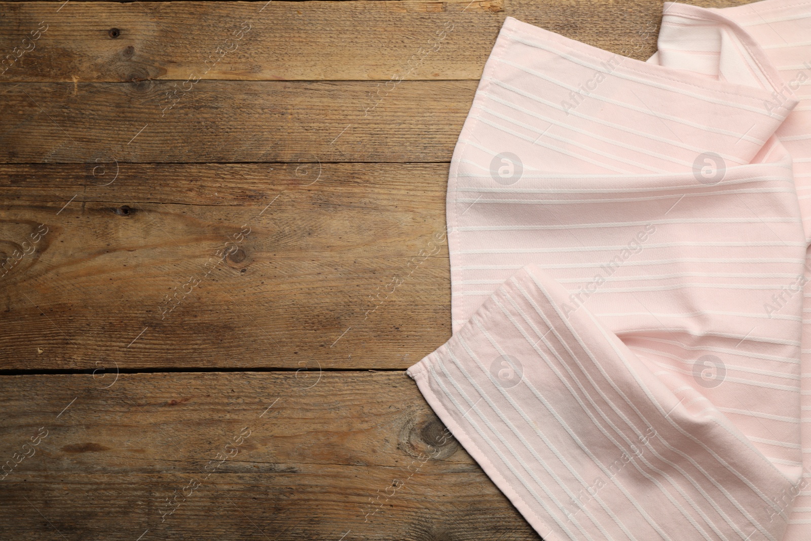 Photo of Pink striped kitchen towel on wooden table, top view. Space for text