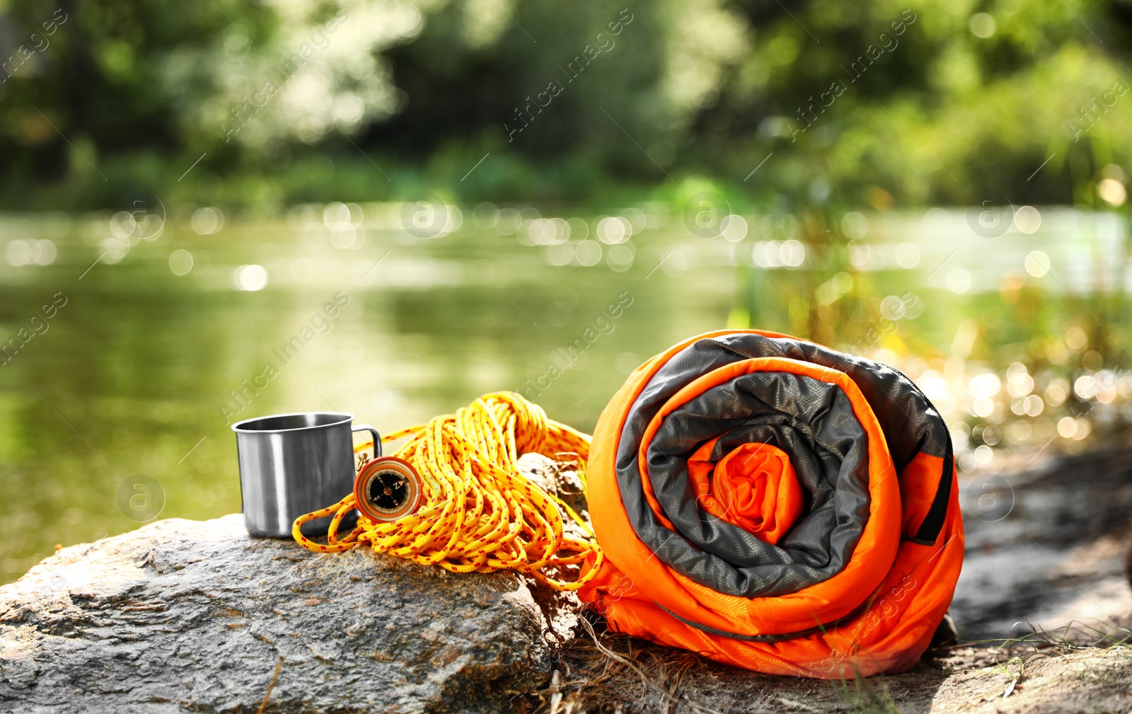 Photo of Rolled sleeping bag and other camping gear near lake