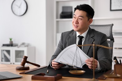 Happy notary working at wooden table in office, space for text