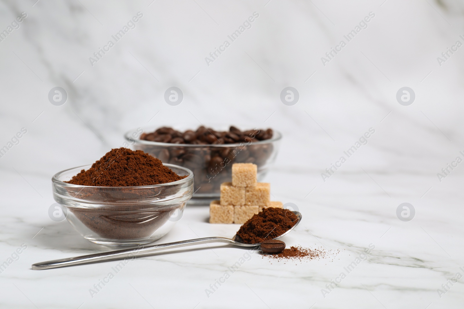 Photo of Glass bowl and spoon with instant coffee on white marble table. Space for text