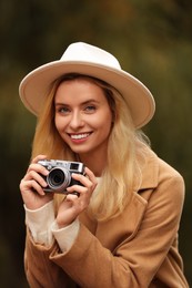 Autumn vibes. Portrait of happy woman with camera outdoors
