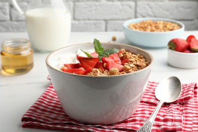 Photo of Bowl with tasty granola and strawberries served on white table. Healthy meal
