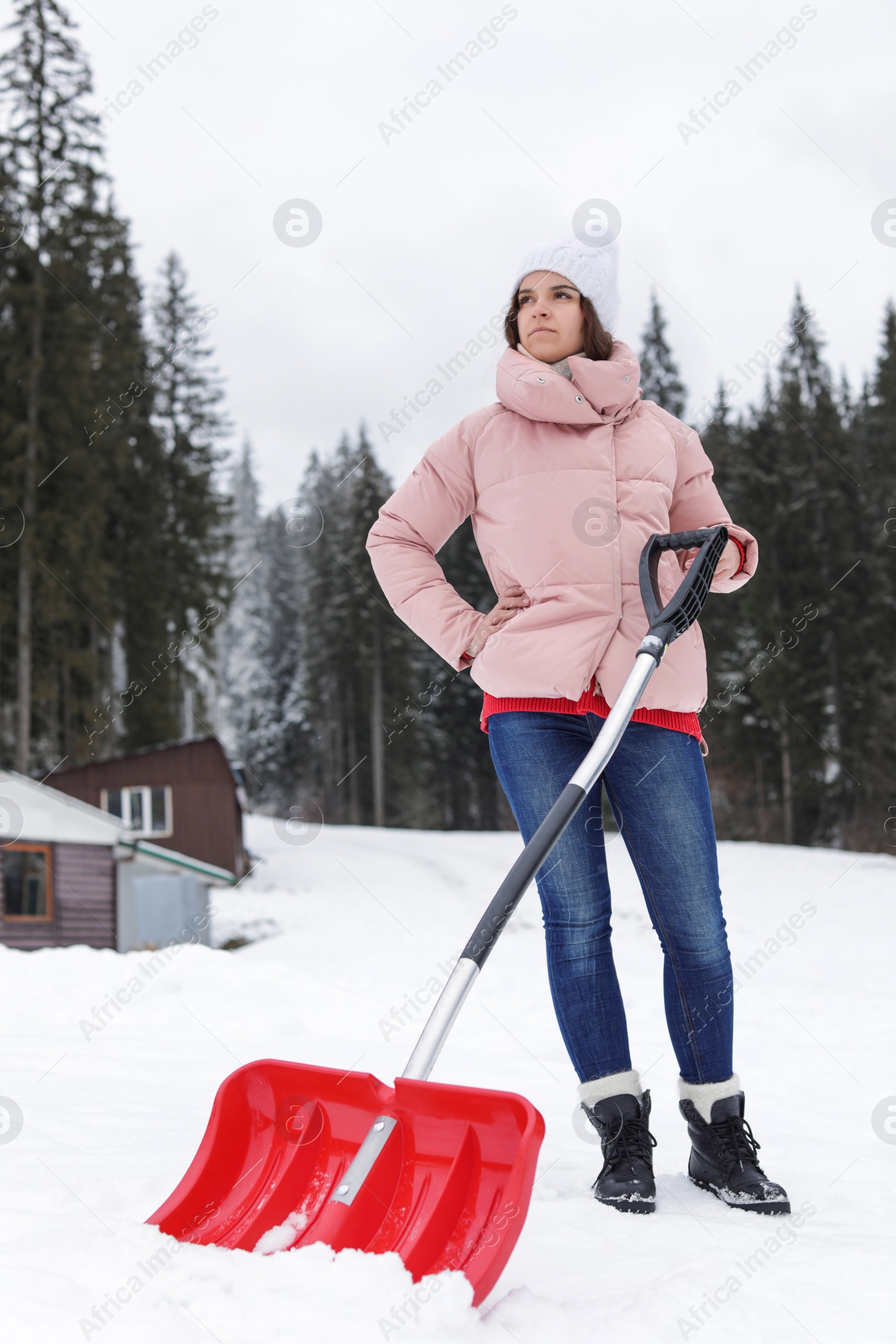 Photo of Woman with shovel for cleaning snow near house outdoors