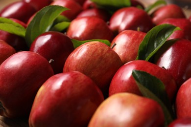 Photo of Fresh ripe red apples with leaves as background, closeup