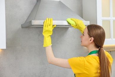 Woman cleaning kitchen hood with rag indoors