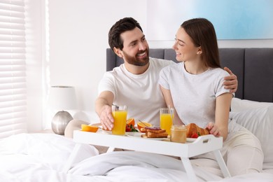 Happy couple having breakfast in bedroom. Space for text