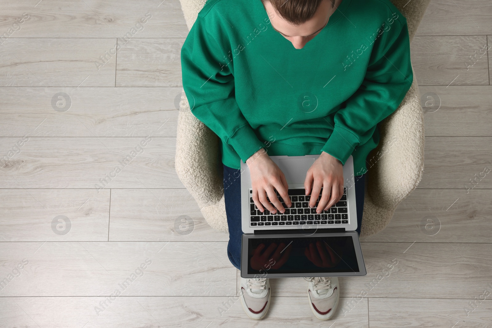 Photo of Man working with laptop in armchair, top view. Space for text