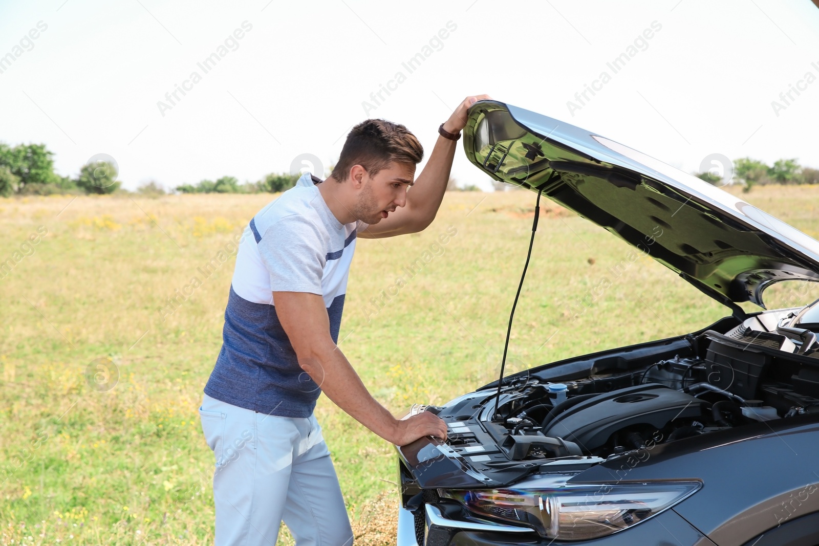 Photo of Man near broken car on country road