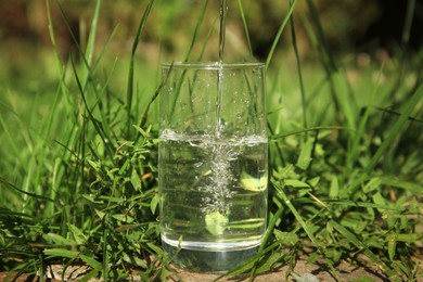 Photo of Pouring pure water into glass outdoors on sunny day