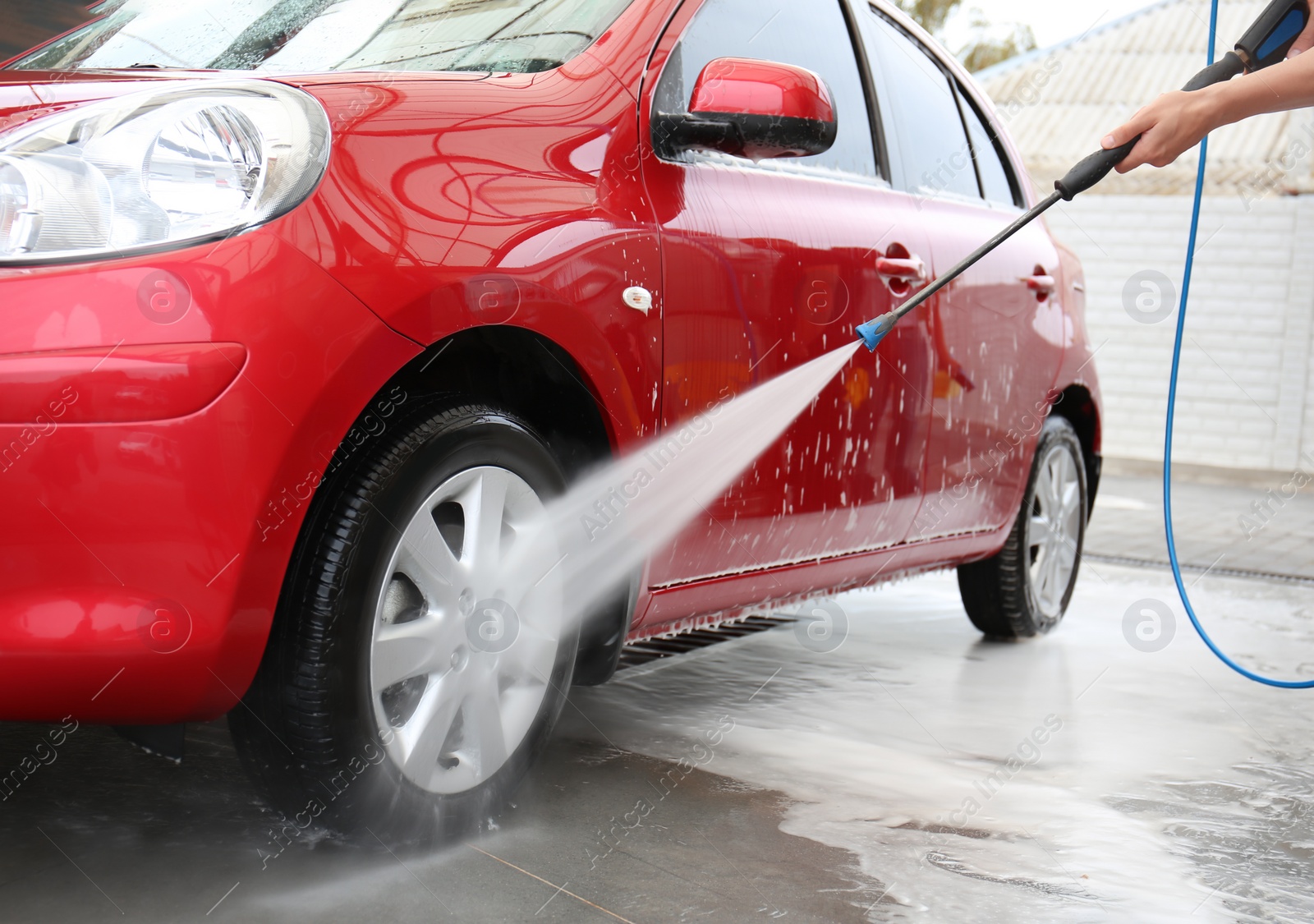 Photo of Male worker cleaning vehicle with high pressure water jet at car wash