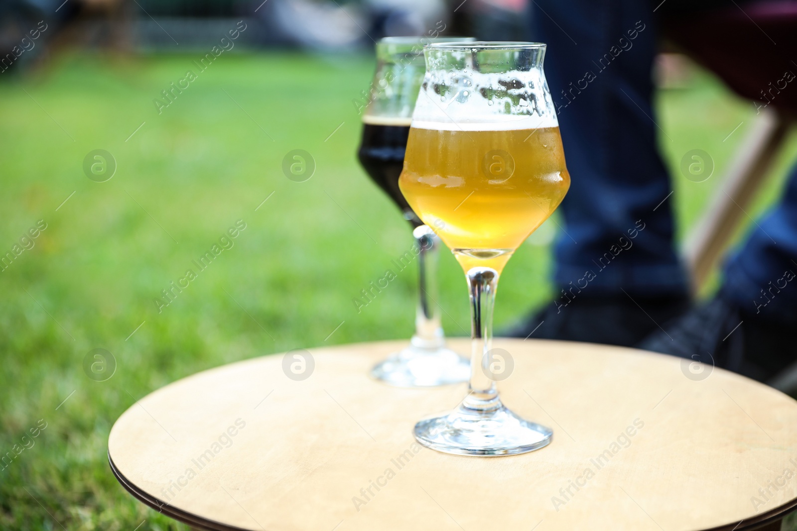 Photo of Cold tasty light and dark beer on table outdoors. Space for text