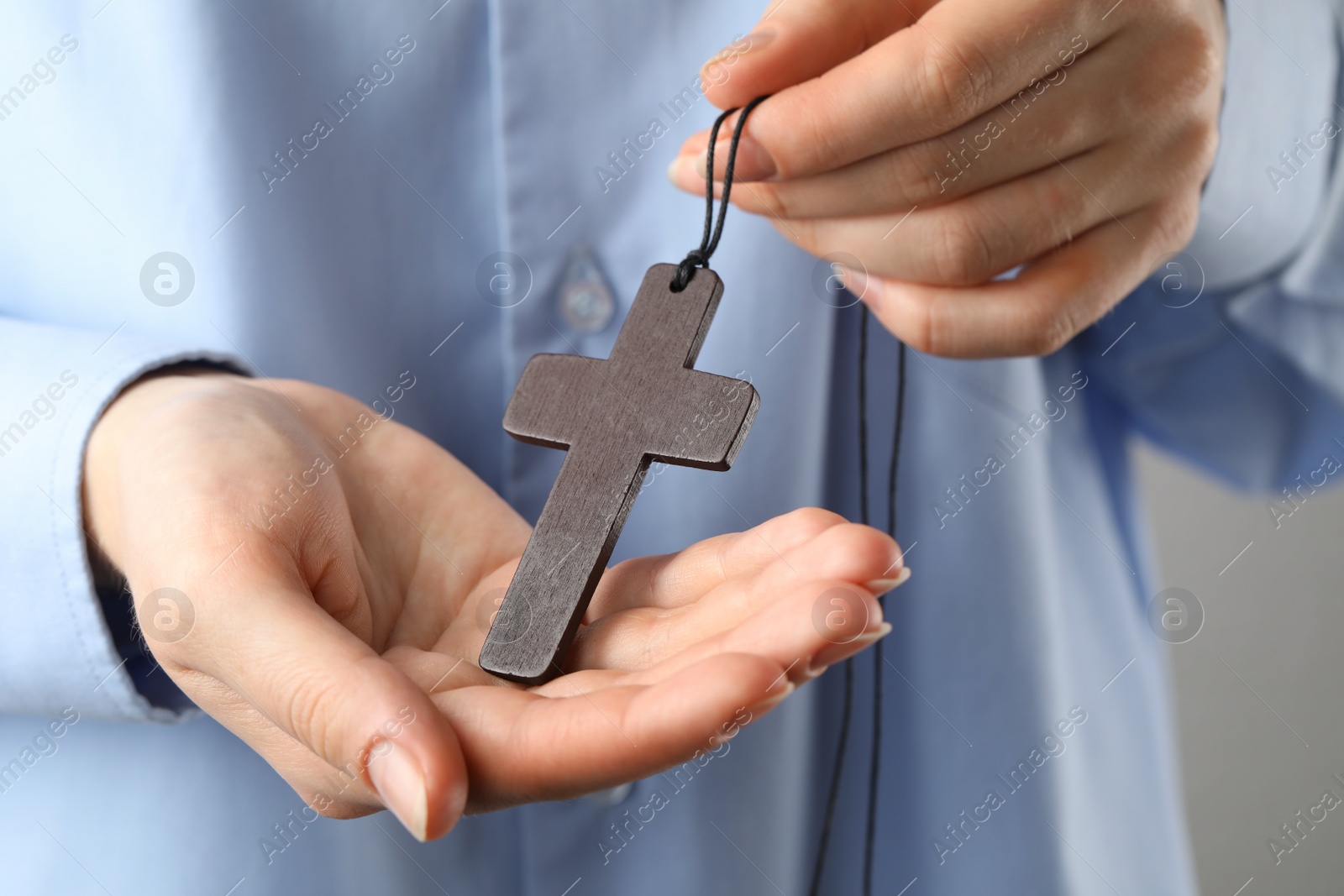 Photo of Woman holding wooden Christian cross, closeup view