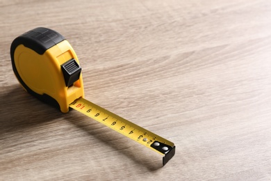 Photo of Metal measuring tape on wooden background. Space for text