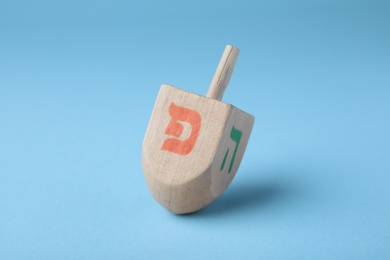 Hanukkah traditional dreidel with letters Pe and He on light blue background