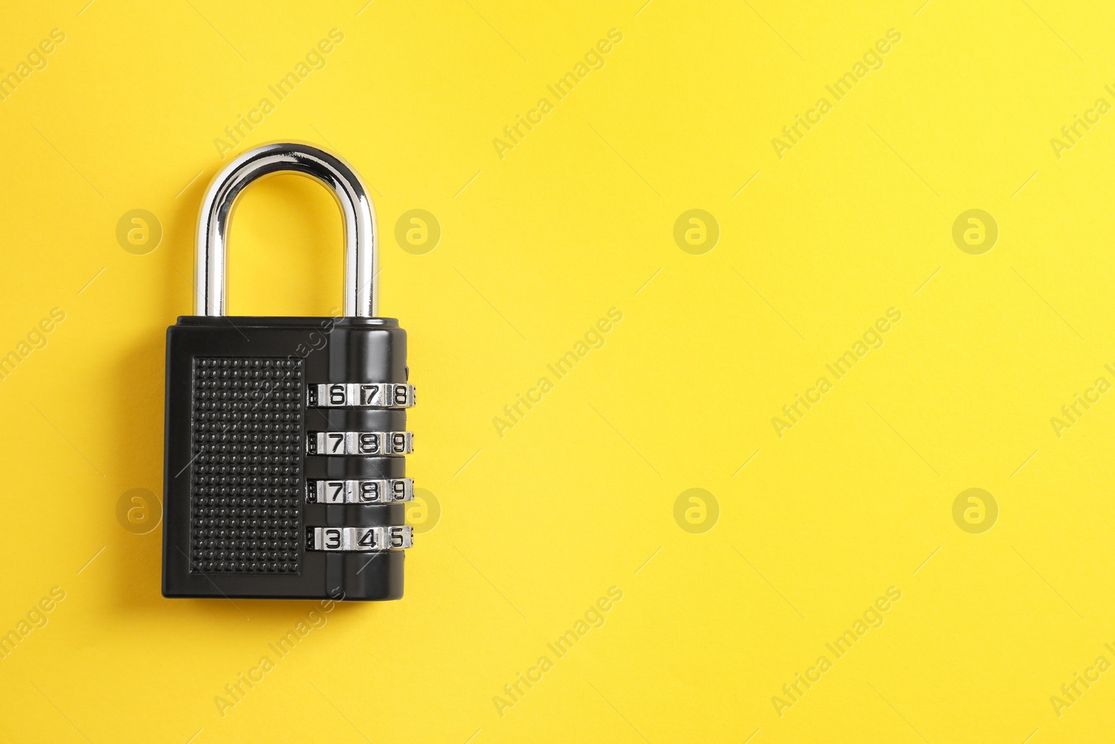 Photo of Steel combination padlock on yellow background, top view. Space for text