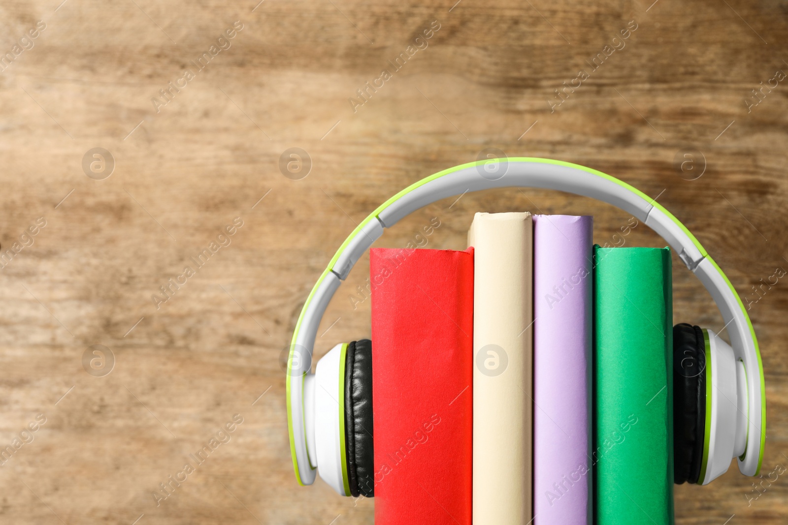 Photo of Books and modern headphones on wooden background, closeup. Space for text