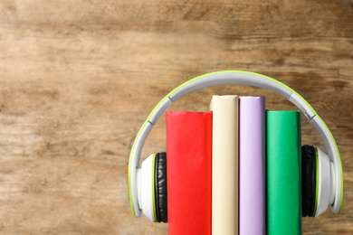 Books and modern headphones on wooden background, closeup. Space for text