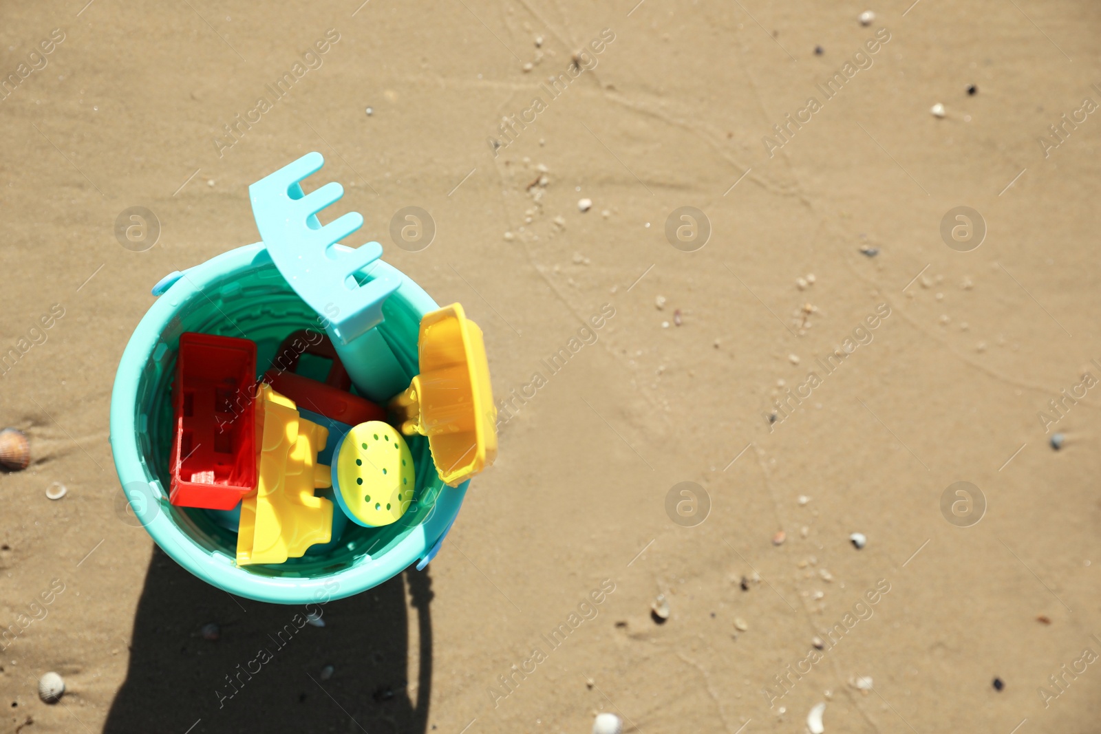 Photo of Different child plastic toys on sandy beach, top view. Space for text