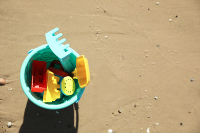 Photo of Different child plastic toys on sandy beach, top view. Space for text