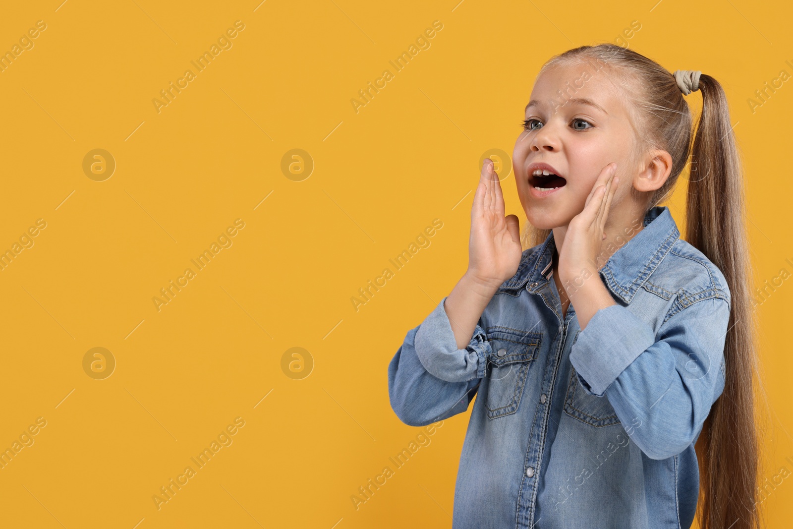 Photo of Special promotion. Little girl shouting to announce information on orange background. Space for text