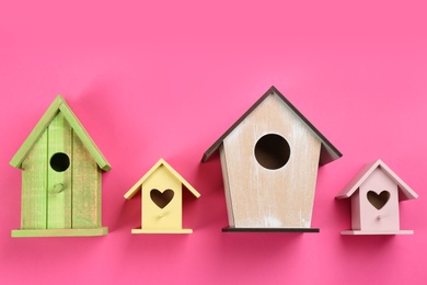 Beautiful bird houses on pink background, flat lay