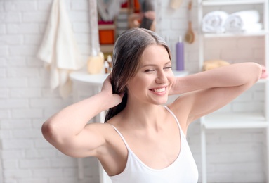 Young woman applying mask onto hair at home