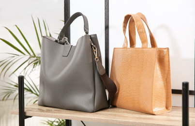 Photo of Different stylish woman's bags on wooden shelf