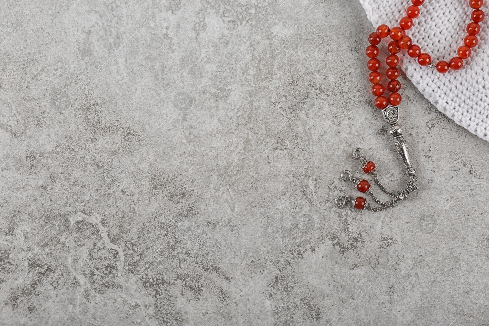 Photo of Muslim prayer beads, cap and space for text on grey background, top view