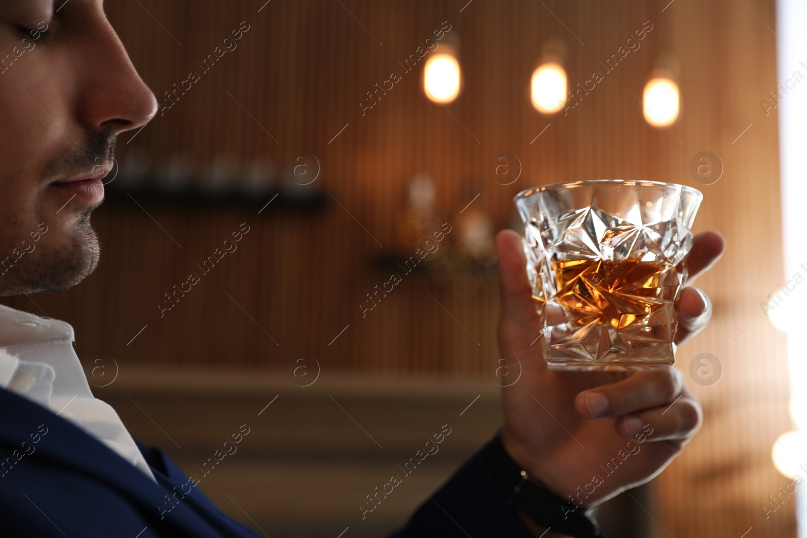 Photo of Young man with glass of whiskey indoors, closeup