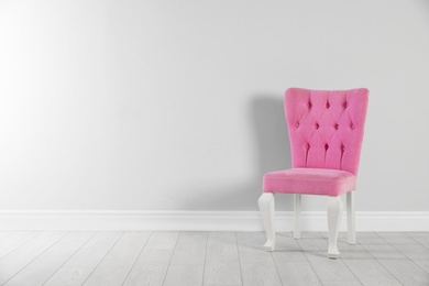 Photo of Stylish pink chair near white wall. Space for text