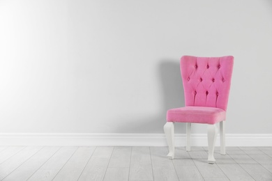 Stylish pink chair near white wall. Space for text