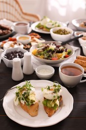 Photo of Delicious sandwiches and many different dishes served on buffet table for brunch