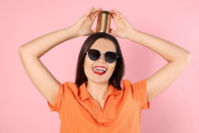 Photo of Beautiful young woman holding tin can with beverage on pink background